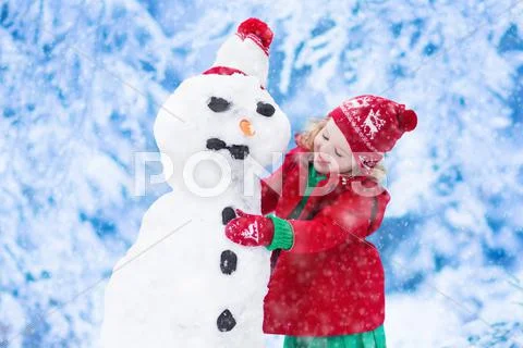 Little girl building a snow man in winter Stock Photos