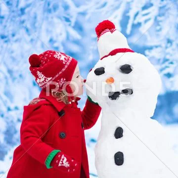 Little girl building snow man in winter Stock Photos