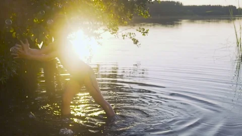 Little girl catches soap bubbles standing in water Stock Footage