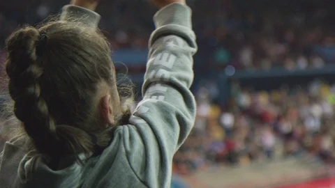 Little girl cheering inside large sports stadium. Audience spectator. Stock Footage