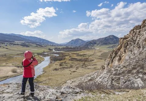 A little girl, a child takes pictures of the landscape from a high mountain Stock Photos