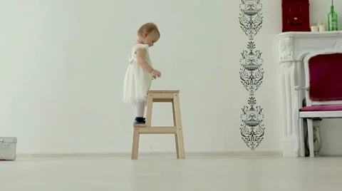 Little girl climbs on a step ladder and claps Stock Footage