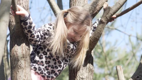 A little girl climbs on a tree while walking with her dad Stock Footage 129778396