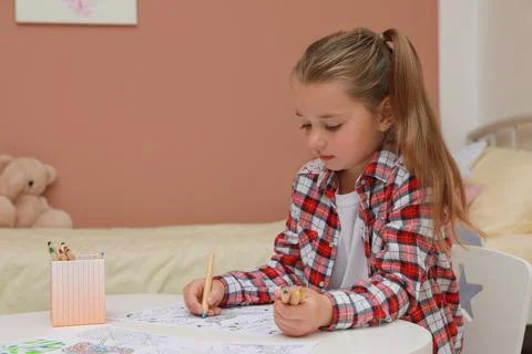 Little girl coloring antistress page at table indoors Stock Photos