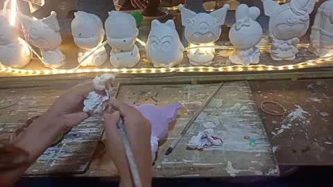 Little girl coloring a three dimensional plaster piggy bank Stock Footage 325763553