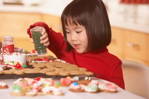 Little girl decorating gingerbread men Stock Photos