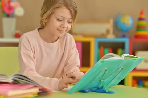Little girl doing homework at the table at home Stock Photos