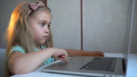 Little girl doing homework using laptop at home, studying online interact Stock Footage 169661236