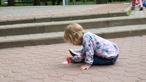 The little girl draws on the asphalt. Stock Footage