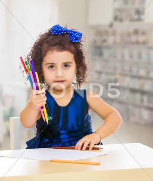 Little girl draws at the table with pencils Stock Photos