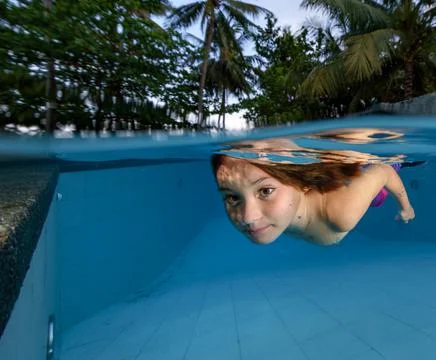 Little girl dressed as a mermaid swims underwater in the pool Stock Photos