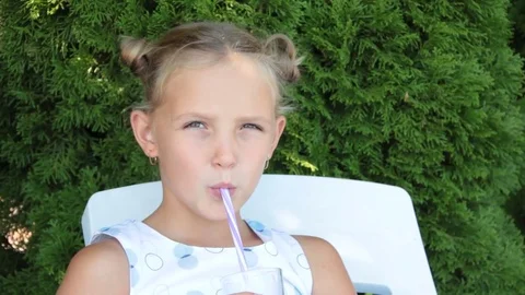 Little girl drinks from a straw Stock Footage