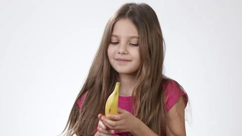 Little girl eating a ripe yellow banana Stock Video Pond5