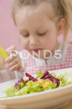 Little girl eating salad leaves with sweetcorn Stock Photos
