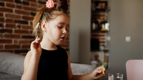 A little girl is eating spaghetti pasta with sausage and nuggets at the table Stock Footage