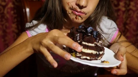 A little girl eats cake with fresh berries. her face in chocolate, she is happy Видео 80896315