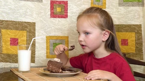 Little girl eats cake using a spoon. A happy child loves sweetness. Video stock 136240777