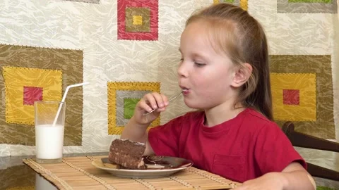 Little girl eats cake using a spoon. A happy child loves sweetness. Stock Footage 136478105