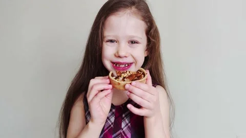 Little girl eats cake with walnuts and caramel. Kid is enjoying a sweet cake. Stock Footage 170612065