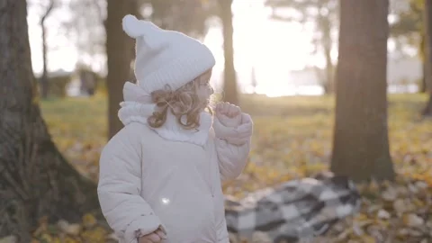 A little girl eats a candy on a stick in park. Kid with candy. Happy baby face Stock Footage 223689762
