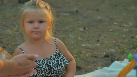 Little girl eats a croissant and tries a colorful candies from female's hand Stock Footage