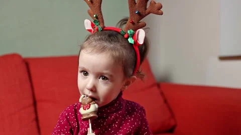 A little girl eats a gift from an advent calendar while sitting on the sofa. Stock Footage 289143436
