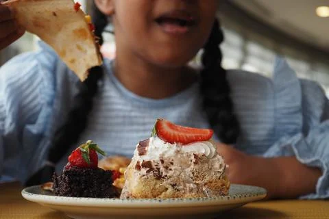 Little girl eats a slice of cafe at a cafe table Stock Photos