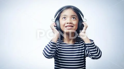 A little girl enjoying listening music by headphone isolated on white background Stock Photos