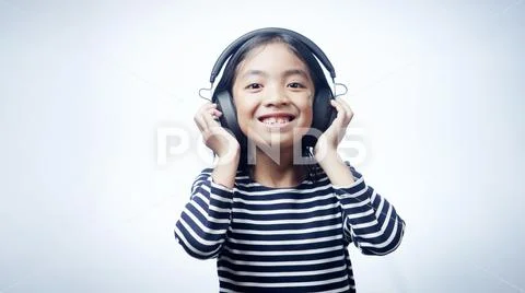 A little girl enjoying listening music by headphone isolated on white background Stock Photos