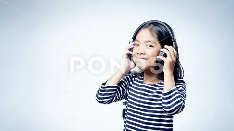 A little girl enjoying listening music by headphone isolated on white background Stock Photos