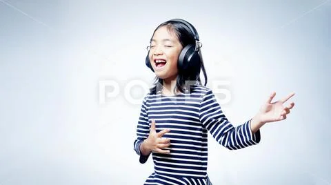A little girl enjoying listening music by headphone isolated on white background Stock Photos