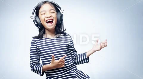 A little girl enjoying listening music by headphone isolated on white background Stock Photos
