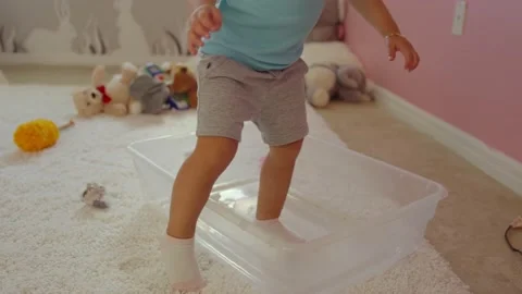 Little girl getting inside a plastic bin in her room and sitting to play Stock Footage 140470937