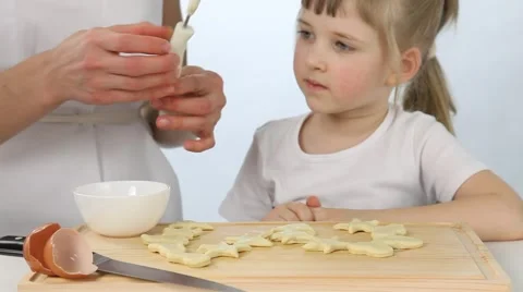 Little girl greasing raw biscuits the yolk Stock Footage 60996224