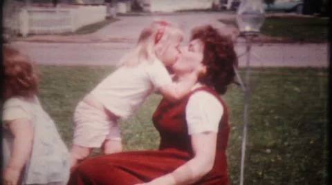 Little girl has kisses for mom in frontyard 1950s vintage film home movie 1359 Stock Footage