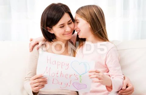 Little girl hugging her mother and holding greating card Stock Photos
