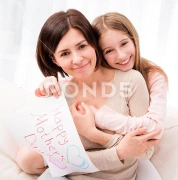 Little girl hugging her mother and holding greating card Stock Photos