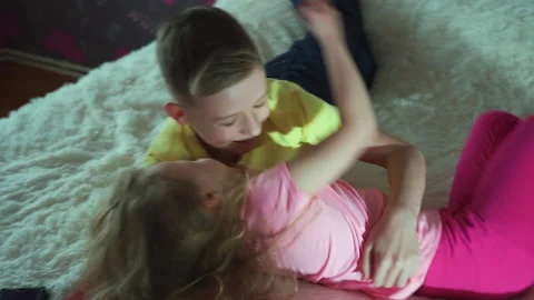 A little girl interferes with homework the boy. Books are lying on the bed. Video stock 132036282
