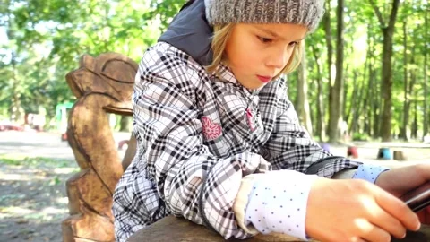 Little girl in a jacket studies the Internet in a mobile mobile phone. City P Stock Footage 155809386