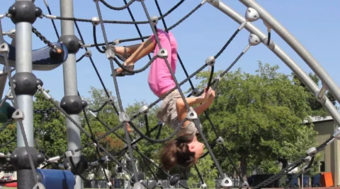 Little Girl on Jungle Gym Swings and Climbs Stock Footage