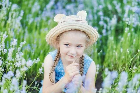 Little girl in lavender field. kids fantasy. Smiling girl sniffing flowers in Stock Photos