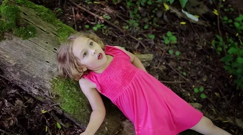 Little Girl Lays Down On A Log And Looks... | Stock Video | Pond5 