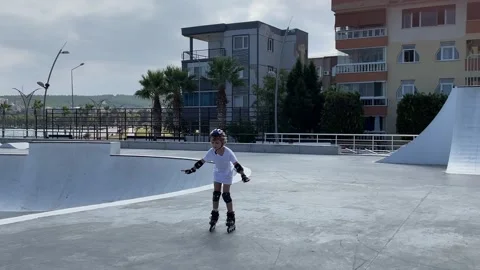 Little girl learn inline skating with roller in public skate park in summer Stock Footage 247845113