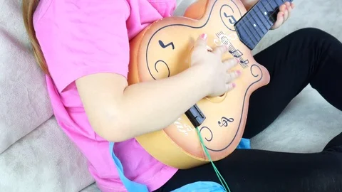 Little girl learning to play basic guitar for self studying at home 스톡 동영상 123607872