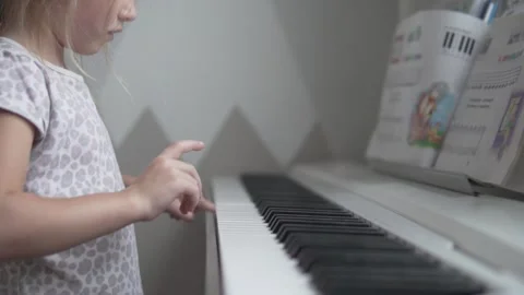 A little girl learns to play the notes on the piano at home Stock Footage 164361255