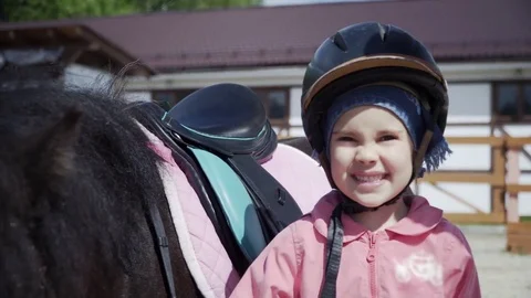 Little girl is looking at camera, posing with the black pony and smiling. Stock Footage 83489130