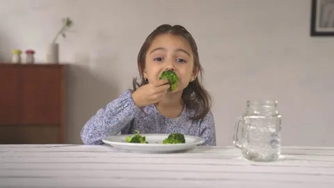 Little girl looking at camera while eating broccoli happily. Stock Footage 241042619