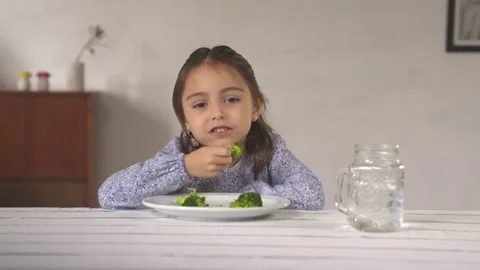 Little girl looking at the camera while eating a broccoli very calmly. Stock Footage 241042632