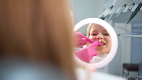 Little girl looking at mirror while dentist doctor doing teeth dental hygienic p Video stock 284039257
