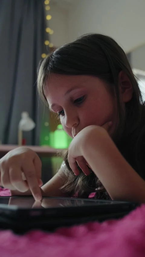Little Girl Lying on Bed Using Digital Tablet at Home Vidéo 343879629